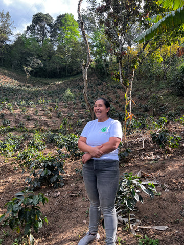 Woman coffee farmer standing with her coffee plants
