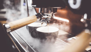 Espresso being poured into two coffee cups 