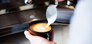 A barista pouring a latte in a cup
